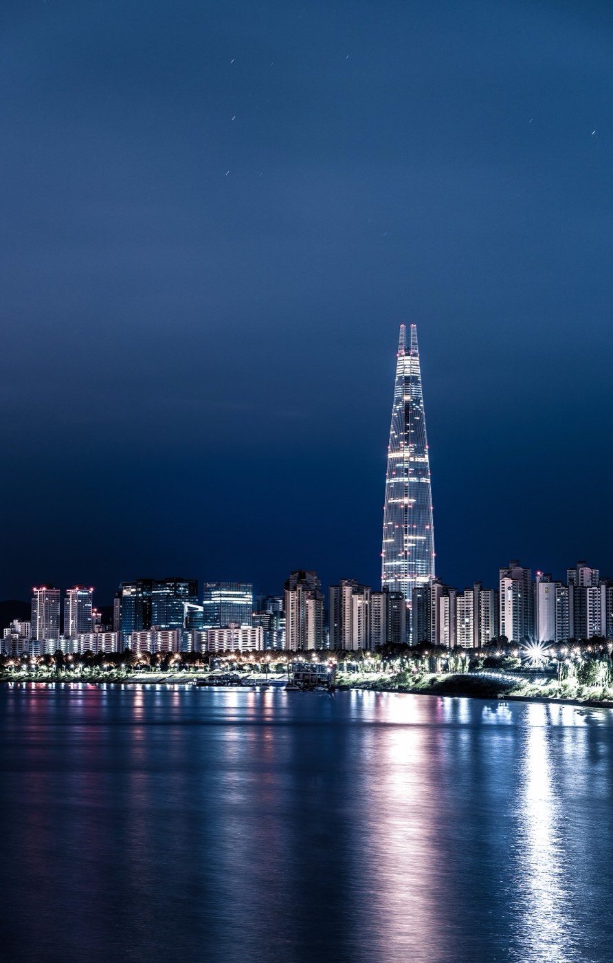The Lotte World Tower lit up at night above the Han River in Seoul