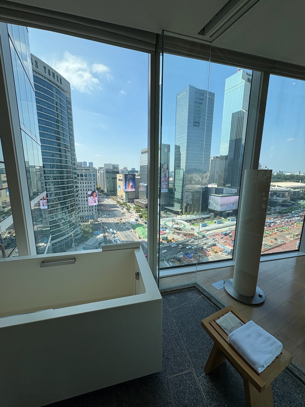 Soaking tub in front of floor-to-ceiling windows looking out at the Gangnam skyline